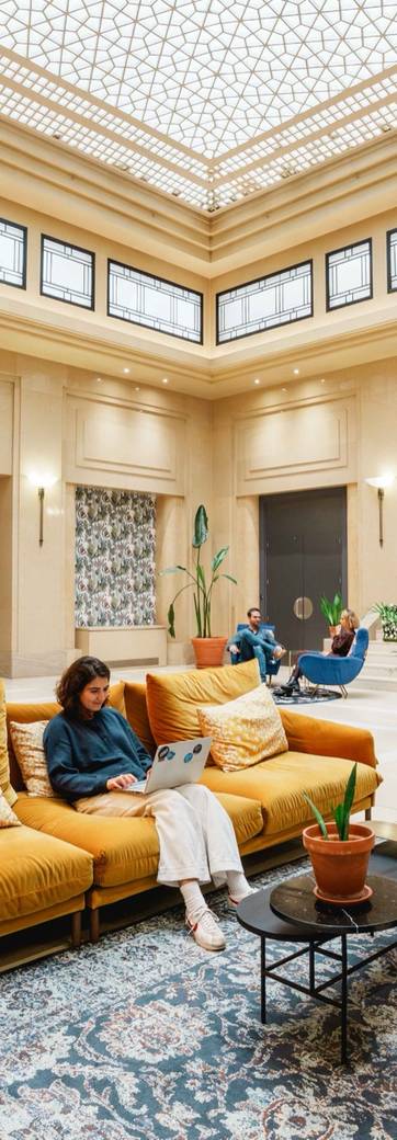 Grand hall d'un espace de coworking sous verrière, avec ses canapés et son accueil