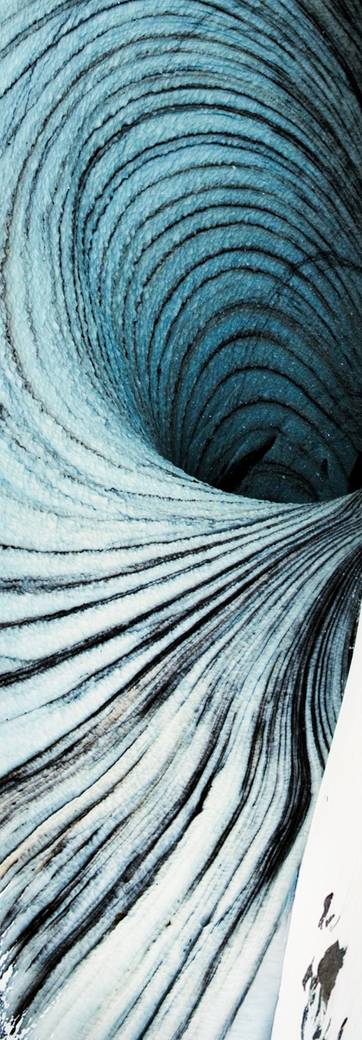 Un puits creusé dans la glace d'un glacier, un marcheur minuscule au bord