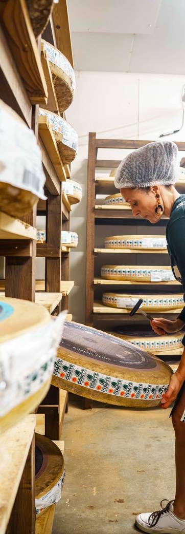 Une fromagère retourne une meule dans une cave d'affinage