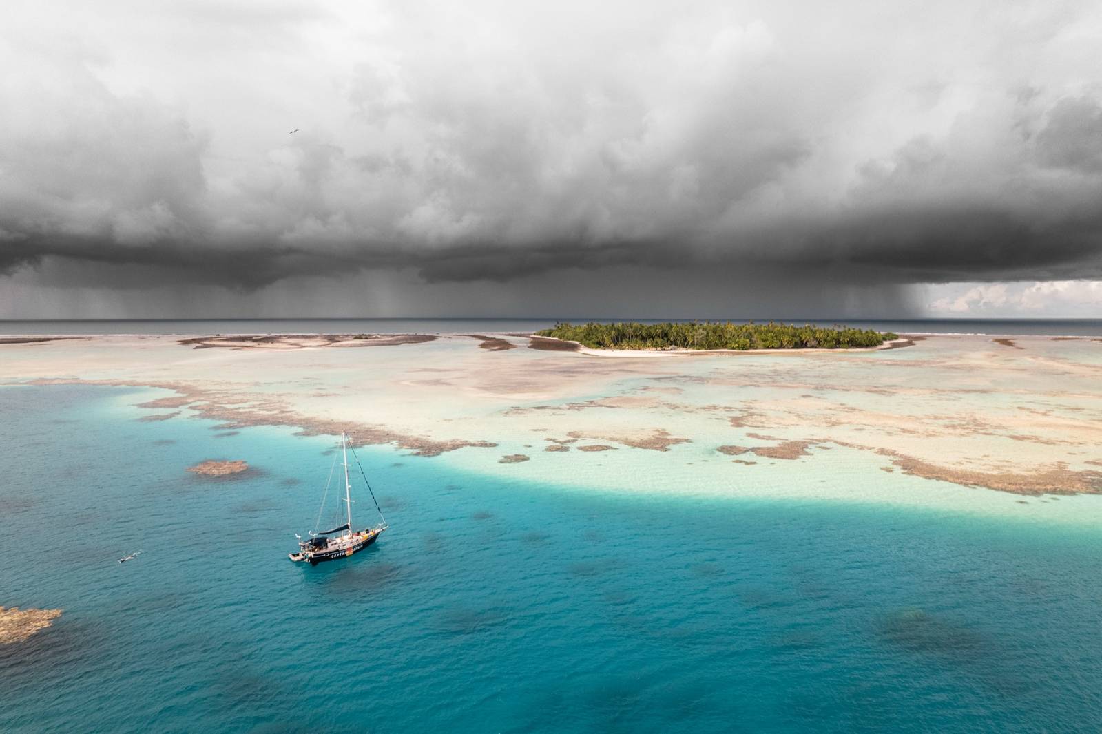 Le bateau Captain Darwin abrité dans un atoll de Polynésie française, pendant que des plongeurs cherchent le corail Porites rus