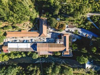 Les toits d'un site ancien entre la forêt et la rivière, vus à la verticale au drone